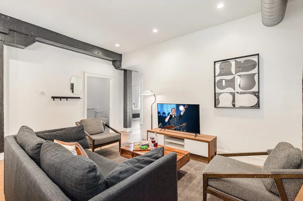 A contemporary living area with a sofa, coffee table, TV, and bold artwork. The setup is designed for movie nights, socializing, or simply relaxing, blending style and comfort.