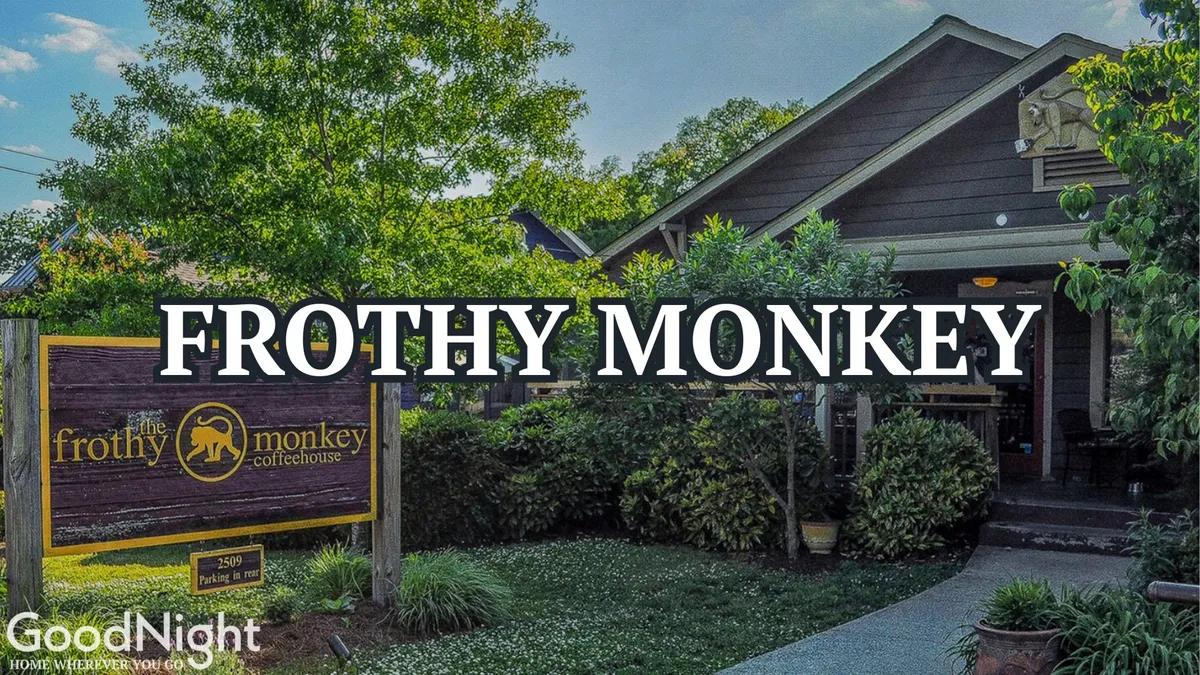 The exterior of Frothy Monkey, with its welcoming signage, landscaped greenery, and an inviting entrance pathway. The scene hints at a popular local coffee spot, perfect for starting a city adventure or gathering with family.